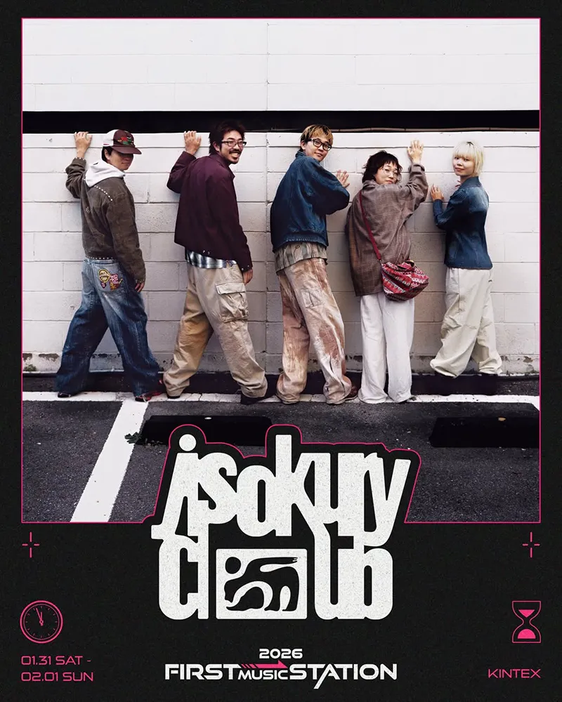 A group of five individuals poses playfully against a white brick wall, showcasing diverse fashion styles. The scene is set in an urban environment with a hint of graffiti. The group exudes a sense of camaraderie, with smiles and relaxed postures.