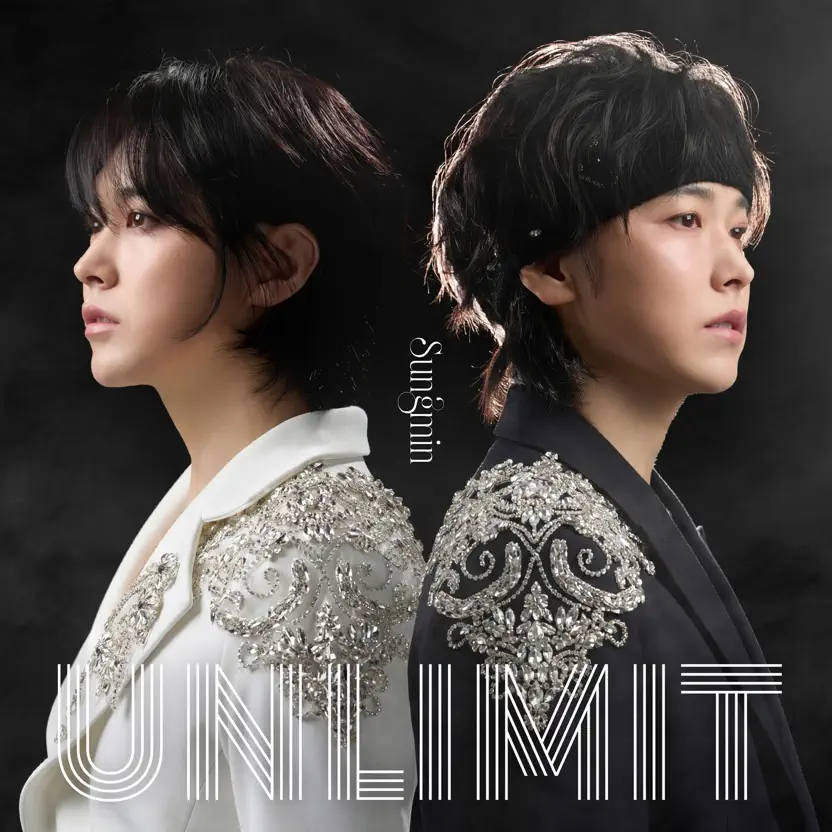 A promotional image featuring two people in profile, one wearing a white outfit and the other in black, both adorned with decorative embellishments on their shoulders. The background is dark, emphasizing their contrasting looks.