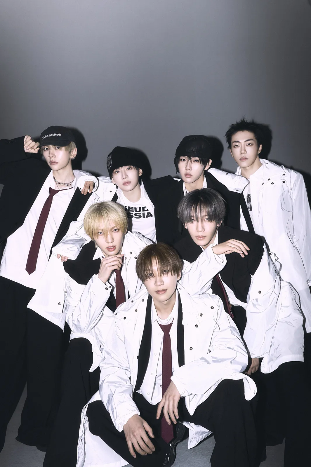 MODYSSEY Members for st Single Album – 1.Got Hooked: An Addictive Symphony (2026). They posing together in stylish outfits, featuring white jackets and ties, against a neutral gray background.