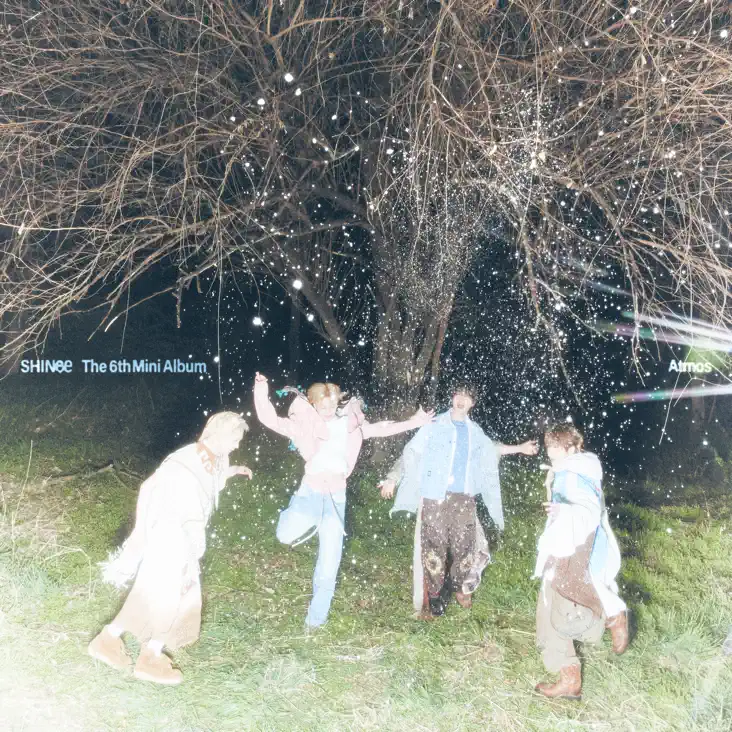 SHINee Atmos Album Cover. Five individuals joyfully playing outdoors at night, surrounded by trees and scattered sparkles, promoting SHINee's 6th Mini Album.